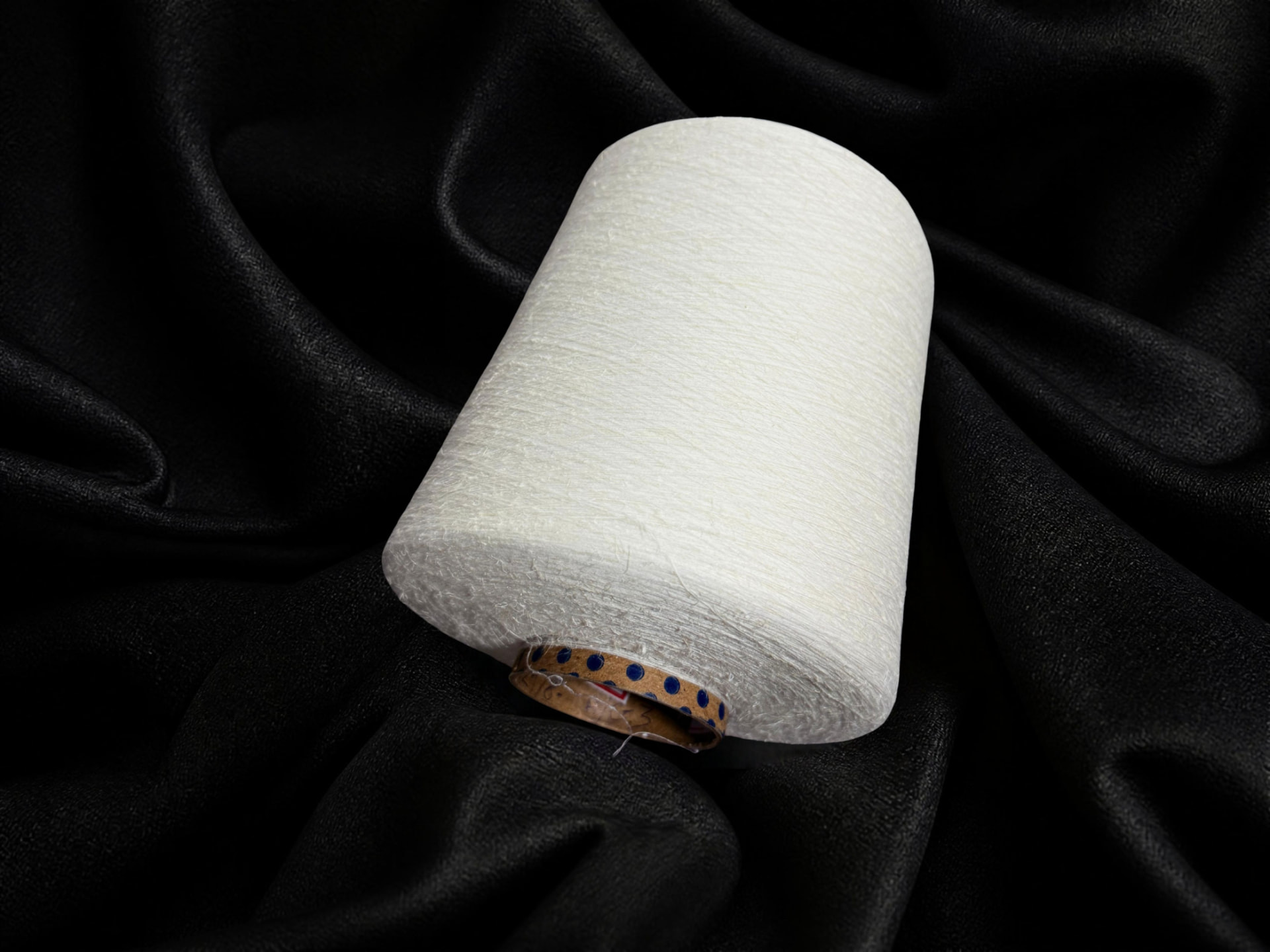 Cream BANACELL banana yarn cone displayed on black fabric